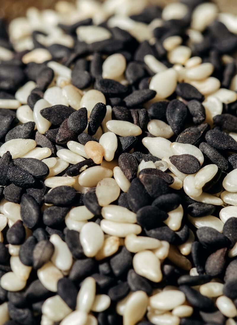 A high-resolution close-up photo of mixed black and white sesame seeds, showcasing texture and detail.